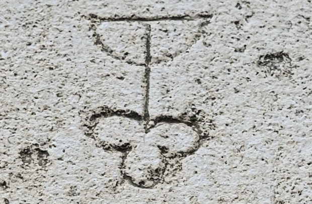 Ein Symbol, das in Stein eingeritzt ist. Es sieht aus wie eine Blume, die auf dem Kopf steht.