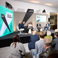 Blick auf eine Bühne, auf der eine Podiumsdiskussion stattfindet