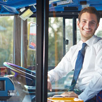 Ein Busfahrer lächelt durch die Scheibe eines Buses © Shutterstock