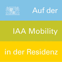 Blauer, grüner und gelber Balken übereinander. In der linken Ecke das kleine Staatswappen. Rechts auf die Balken verteilt der Text "Auf der IAA Mobility in der Residenz" © StMB