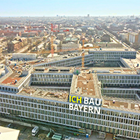 München aus der Vogelperspektive. Im Vordergrund die Baustelle für das neue Justizzentrum. Darauf ist der Schriftzug "Ich bau Bayern" eingeblendet. © StMB