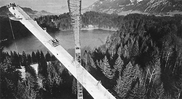 Schwarz-weiß-Foto einer Brücke. Um die Brücke herum Wälder.