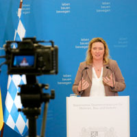 Staatsministerin Kerstin Schreyer zieht nach einem Jahr als Bau- und Verkehrsministerin bei einer Pressekonferenz Bilanz. Sie steht dabei an einem Rednerpult, im Vordergrund ist eine Kamera zu sehen. © StMB