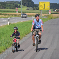 Vater und Sohn radeln auf einem neuen Radweg an der B12 © Bayerisches Staatsministerium des Innern, für Bau und Verkehr